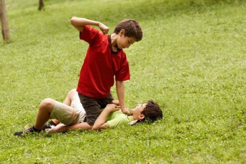 2 børn slår hinanden på en græsplæne