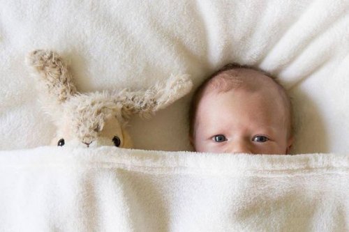 Baby under dyne med bamse. En nyfødt's syn