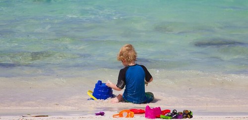 barn sidder og leger på en strand