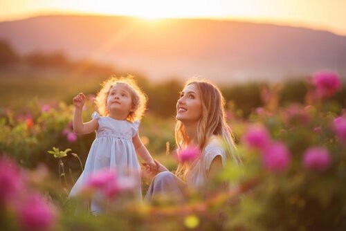 mor og datter på en blomstereng ved solnedgang