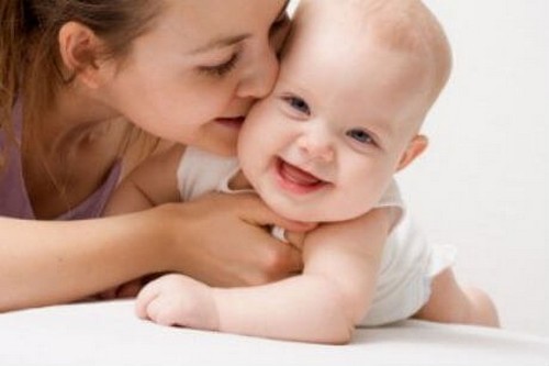 mor kysser sin smilende baby