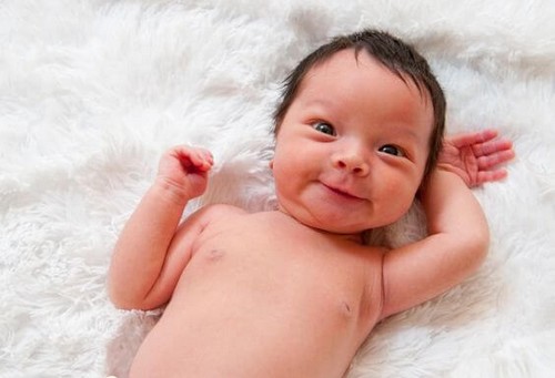 nyfødt baby smiler til verden