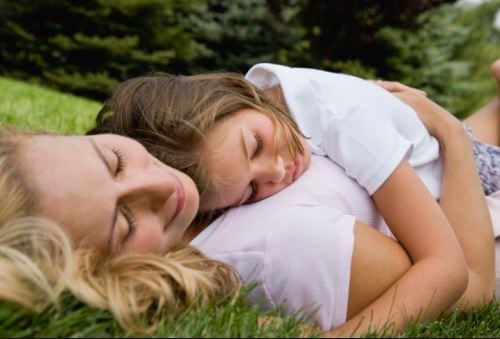 Mor ligger på græsset med datter