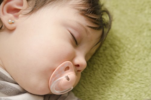 baby med ørering sover. Øreringe for børn.