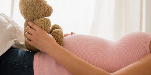 gravid kvinde holder en bamse