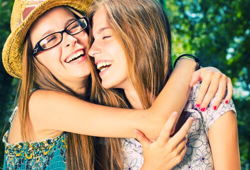 Teenage piger krammer og smiler