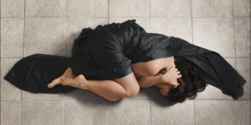 Kvinde ligger på gulvet og er deprimeret 