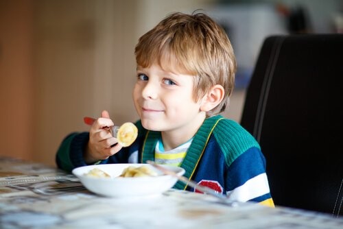 Dreng spiser snack ved køkkenbord