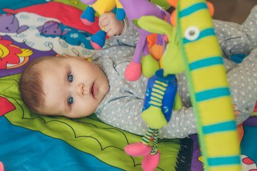 Baby udfører stimulerende øvelser med legetøj