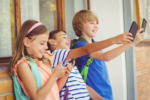 Smilende børn med telefoner frygter ikke teknologiske sygdomme hos børn