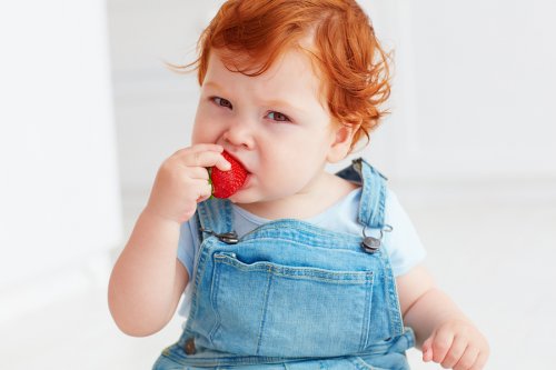 lille barn der spiser et jordbær