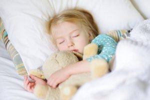 et barn sover trygt med sin bamse