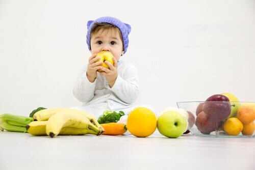 Baby omringet af forskellige frugter 