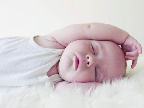 baby der sover med arm over hovedet