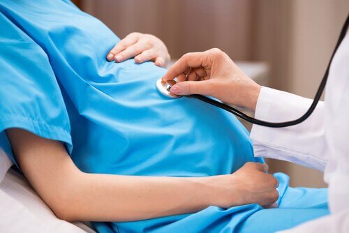 læge der lytter på gravid kvindes mave