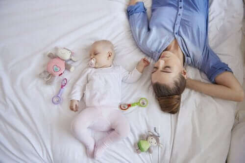mor og baby der sover i seng