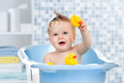 Baby leger med gule badeænder i badekarret 
