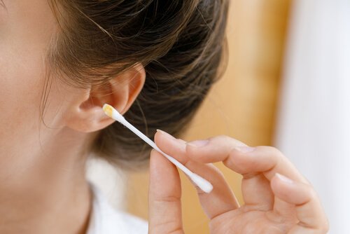kvinde der renser sit øre med en vatpind