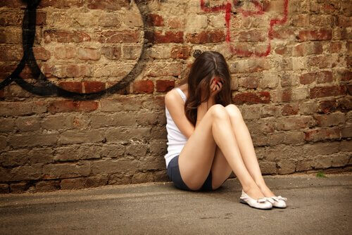 ung, trist kvinde, der sidder op ad væg