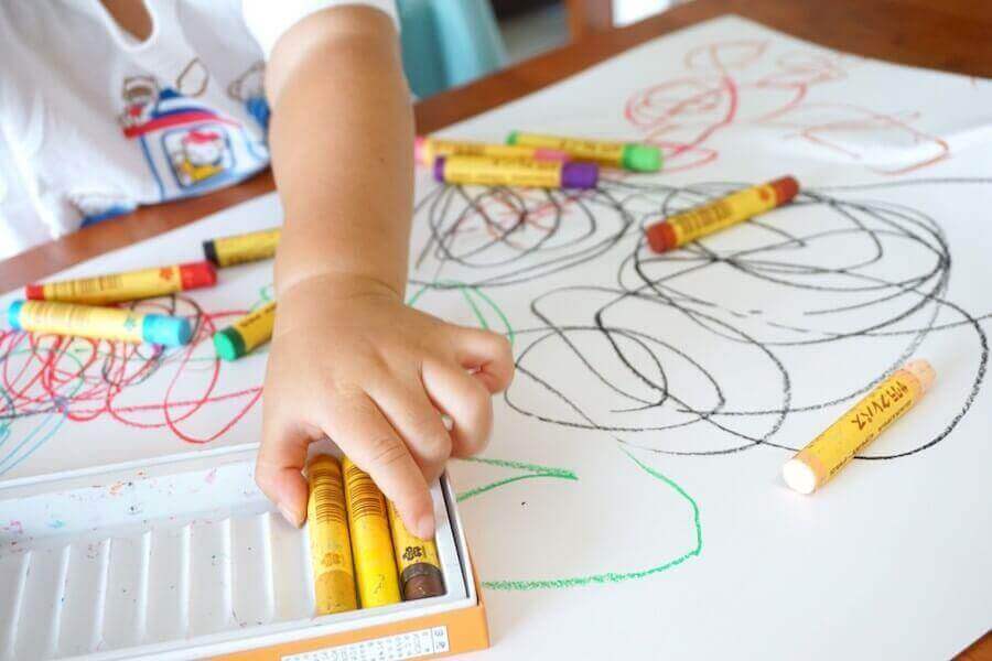 Sådan tolkes farver i børns tegninger: Barn tegner med forskellige farvekridt.