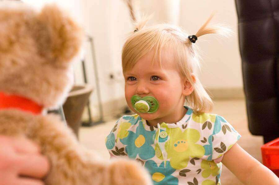 Lille pige med sut og bamse.