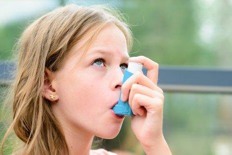 Pige bruger sin inhalator mod astma.