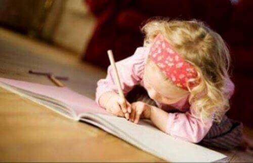 Forfatterbørn: Lille pige ligger på gulvet og skriver i notesbog.