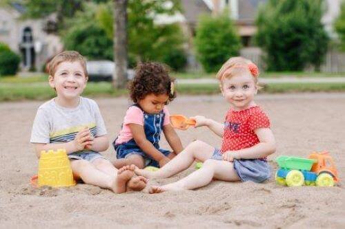 Sociale færdigheder: Små børn leger sammen i sandkasse.
