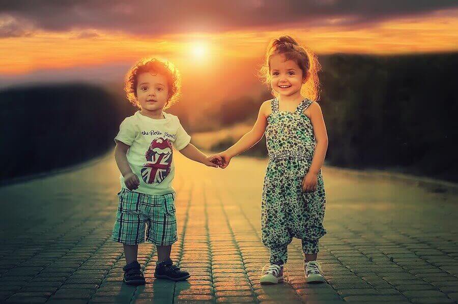 Børn føler beskedenhed. Lille pige og dreng holder i hånden.