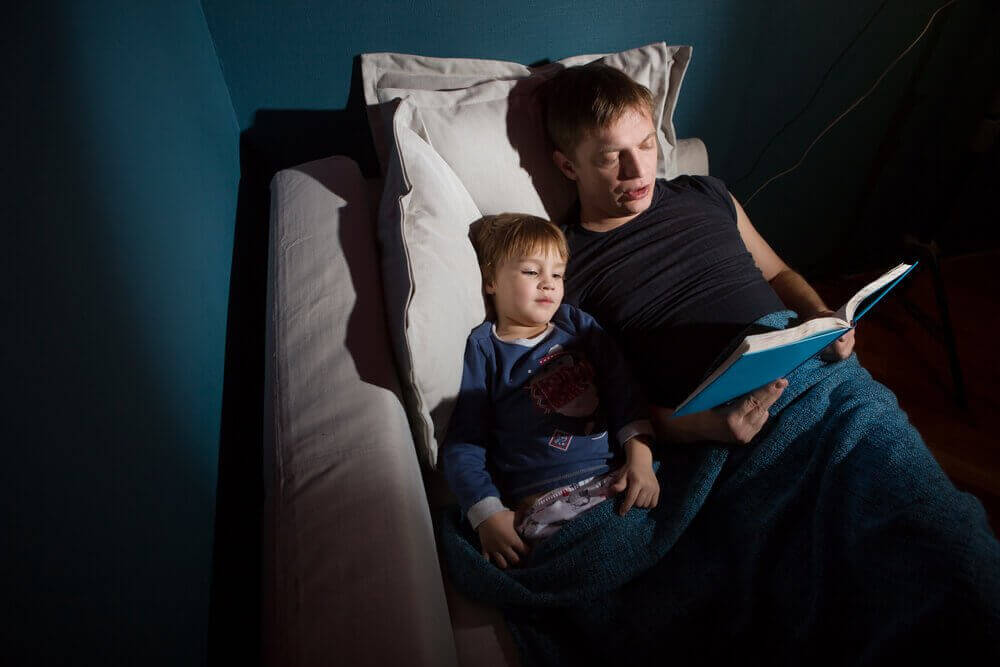 Sådan fortæller du dine børn uhyggelige historier. Far læser højt for sin søn.