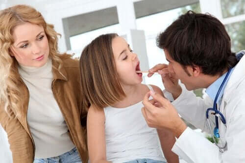 Hvornår skal man fjerne mandlerne hos børn. Læge tjekker piges mund og mandler.
