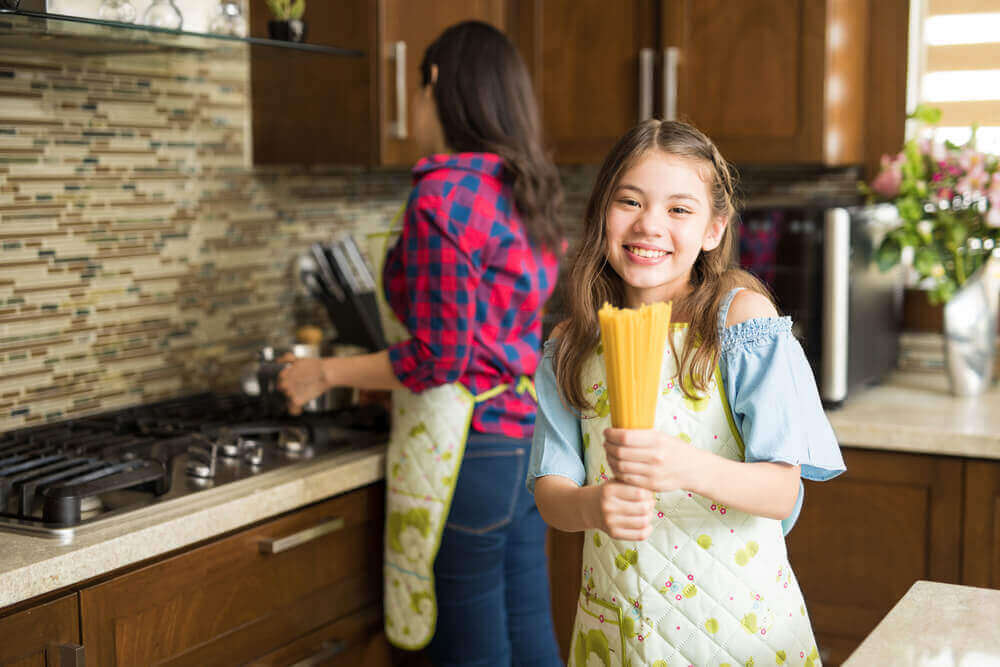 At underholde dine børn mens du laver mad: Pige hjælper mor i køkkenet.
