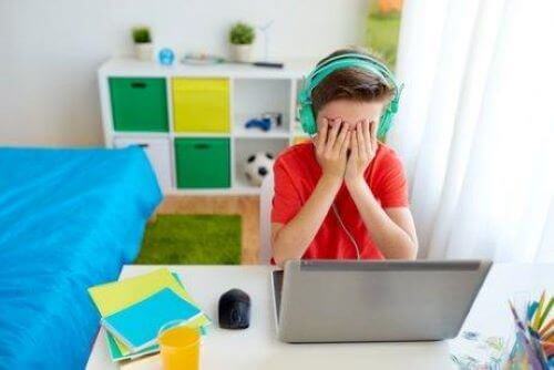 dreng ved computer der holder sig for øjnene