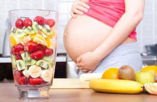 gravid kvinde der laver en stor smoothie