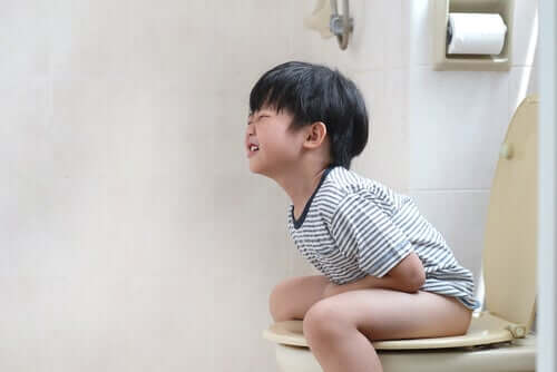 Lille dreng sidder på toilettet med forstoppelse.