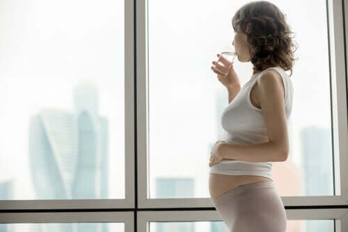 Gravid kvinde drikker et glas vand: Sådan håndterer du fordøjelsesbesvær under graviditeten.