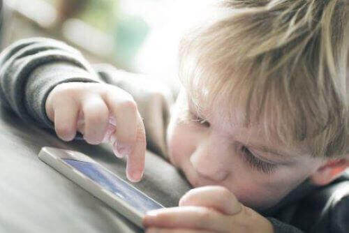 lille dreng der bruger en smartphone