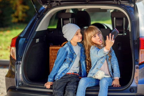 små børn der tager selfie i bagagerum på bil