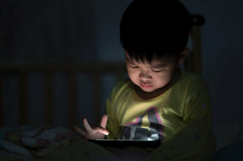 lille dreng der sidder med tablet i mørke