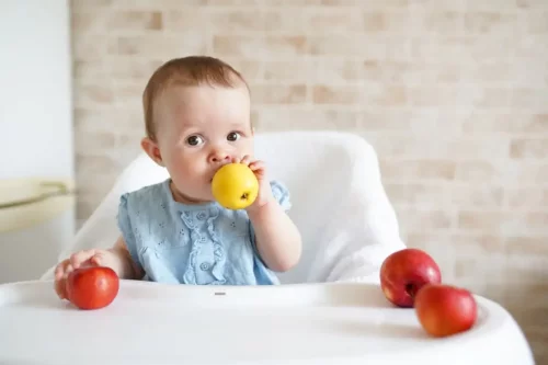 Baby sidder med et æble
