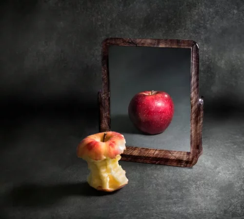 Udmagret æble med fyldigt spejlbillede repræsenterer spiseforstyrrelser