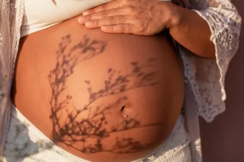 Gravid mave med skygge fra blomst