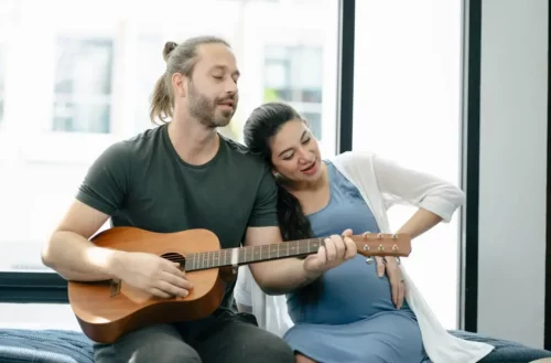 Mand spiller guitar for gravid kvinde