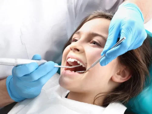 Tandlæge behandler en piges tænder med fluoridlak