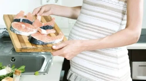 Gravid kvinde tilbereder fisk