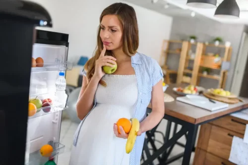 Gravid kvinde står ved køleskab