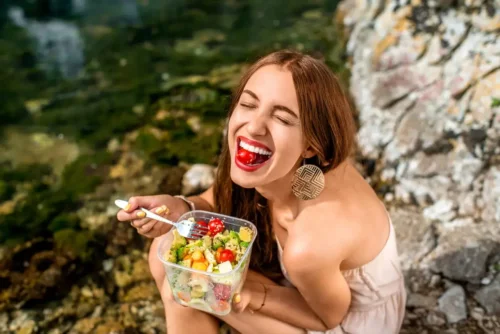 Kvinde spiser en salat ved havet