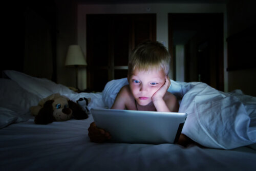 Dreng nyder skærmtid i sengen om aftenen