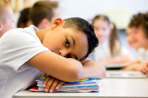 Dreng hviler sit hoved på bøger i skolen