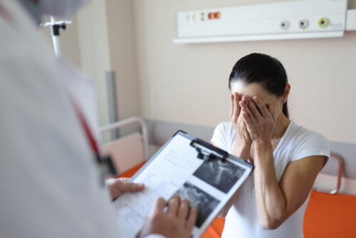 Kvinde står overfor læge, der holder scanningsbilleder